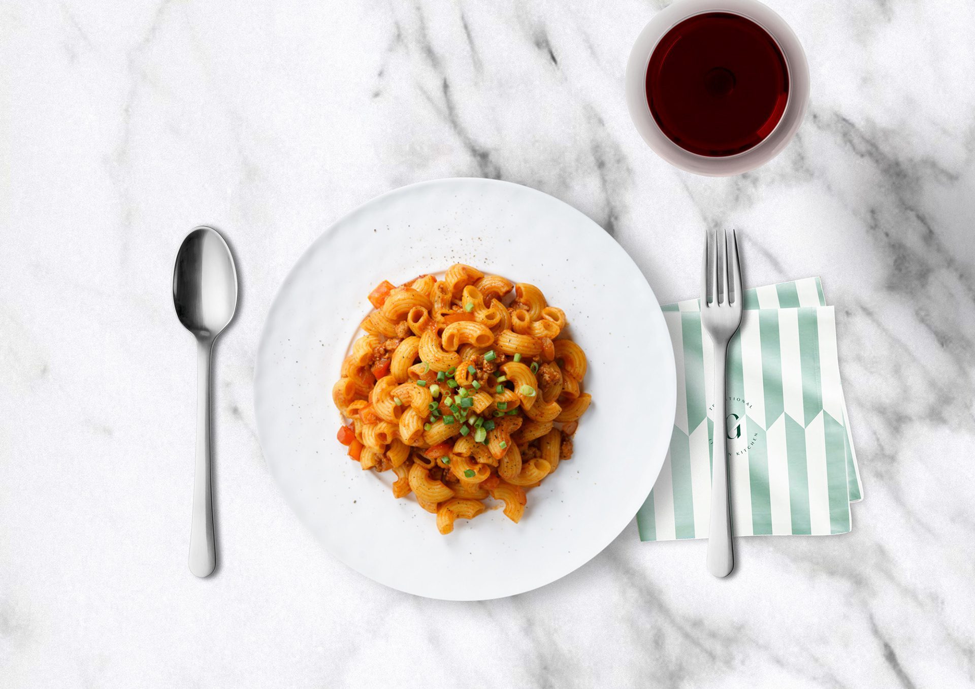 Plate of pasta on marble with cutlery and a striped Gaia napkin