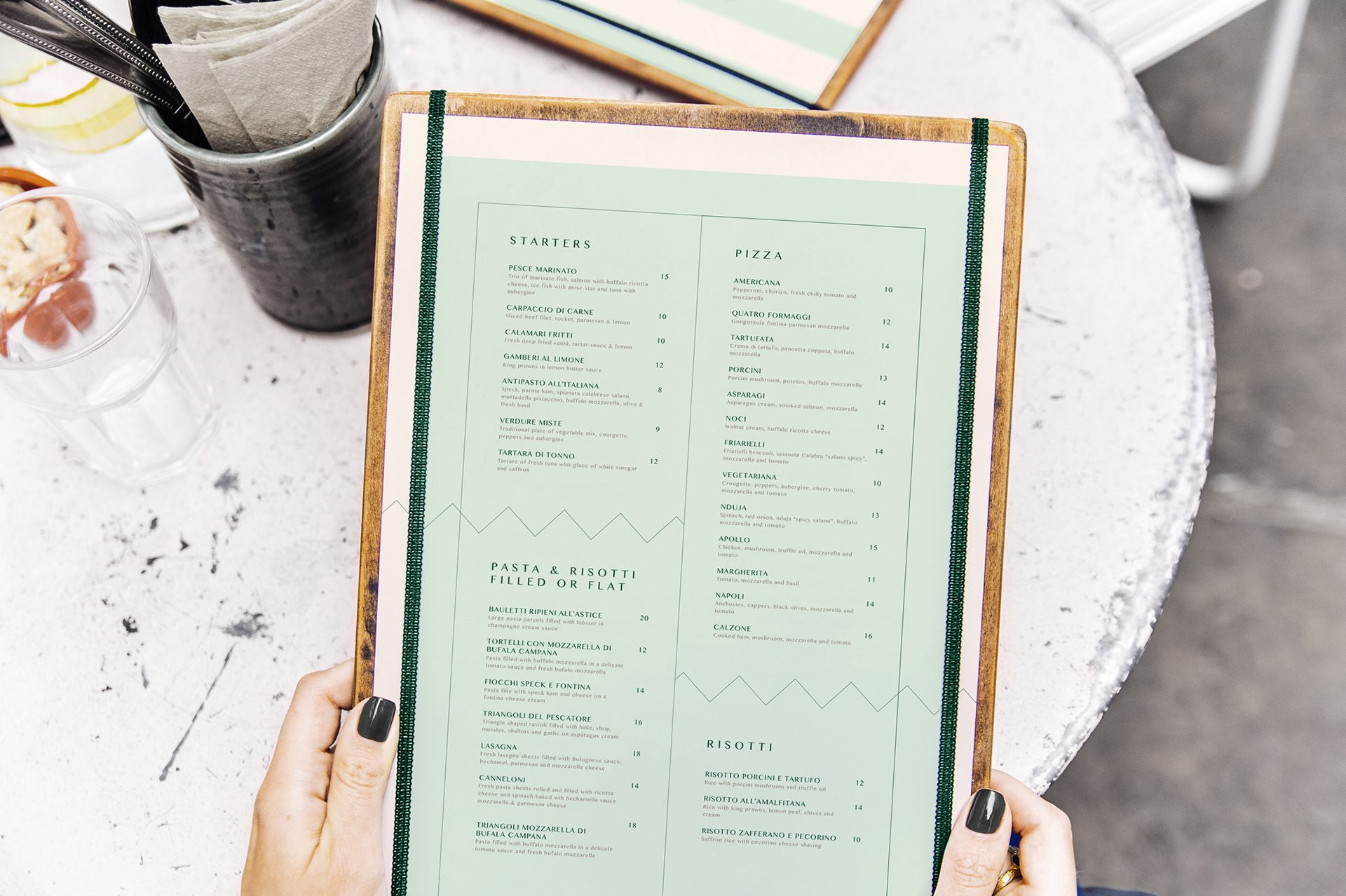 Hands holding a Gaia menu board over a marble table