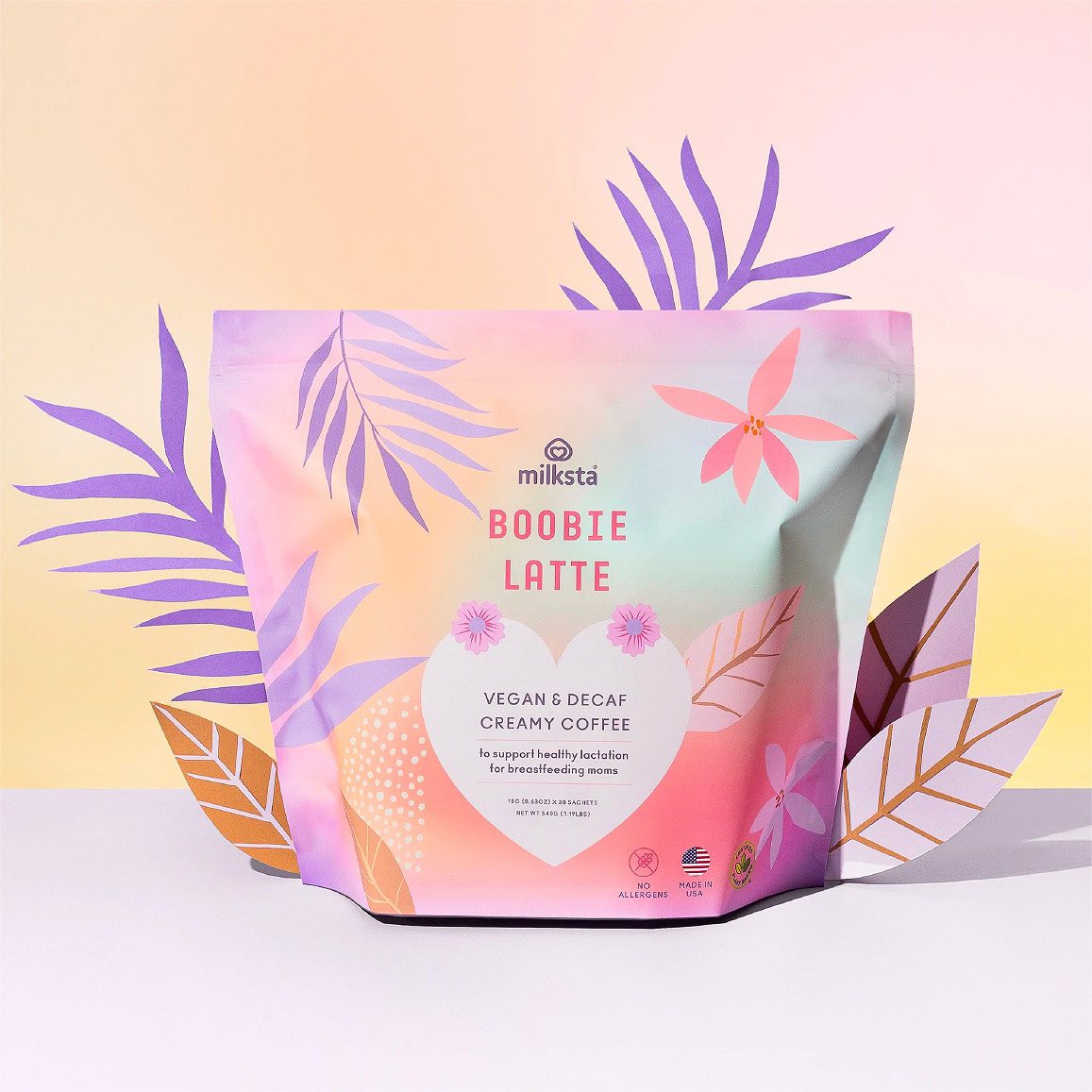 Milksta gradient pouch standing among paper leaves on a peach gradient ground